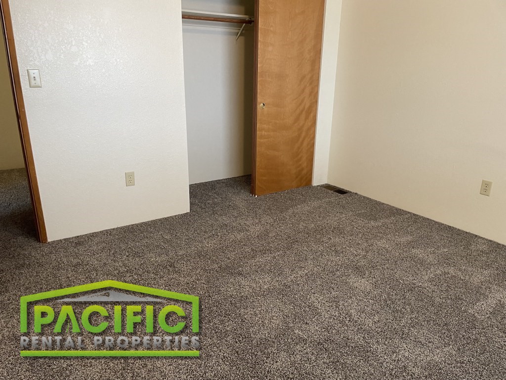 a carpeted room with an open door and a pacitech logo on the floor
