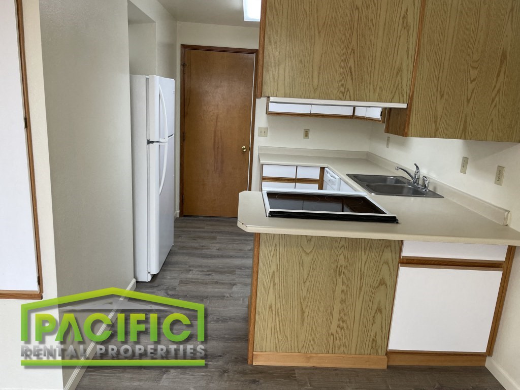 a small kitchen with wooden cabinets and a white counter top