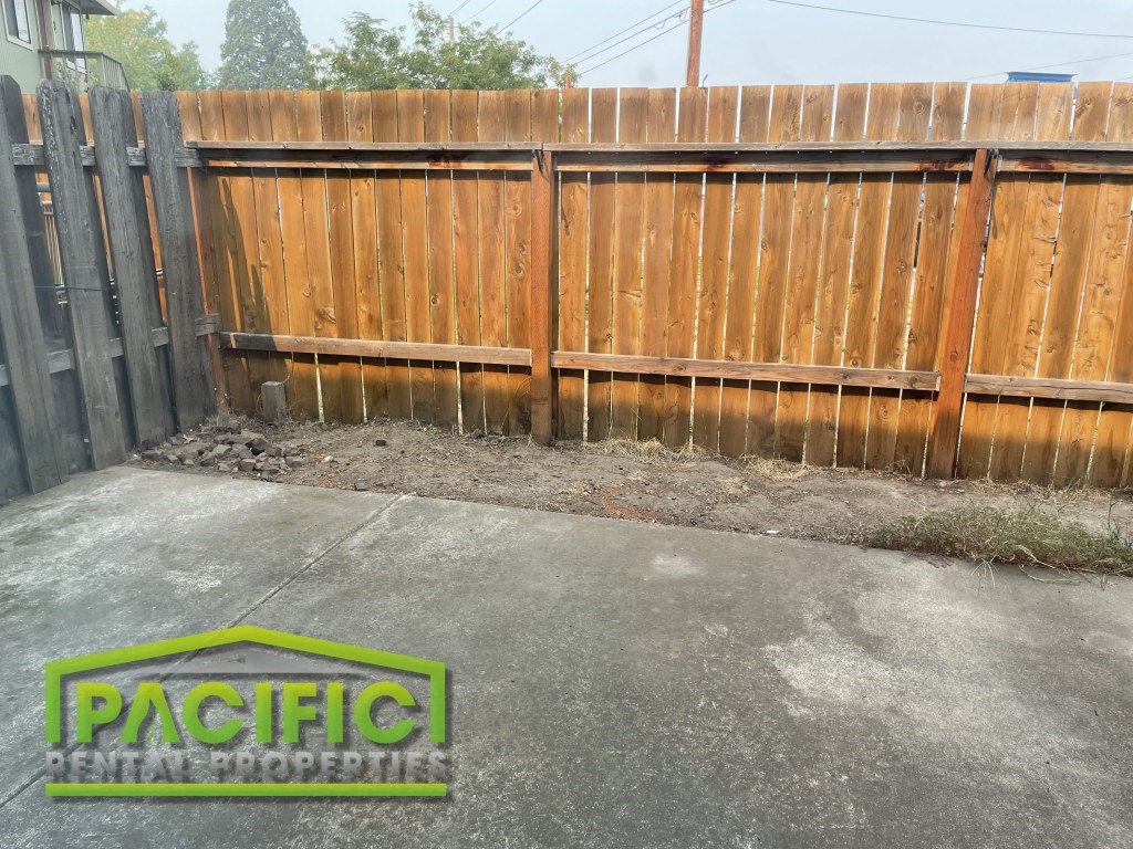 a wood fence with a yard in front of it