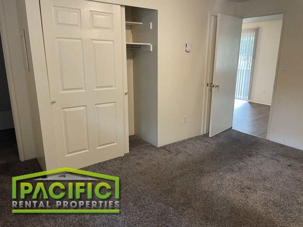 a room with a carpeted floor and a door into a closet