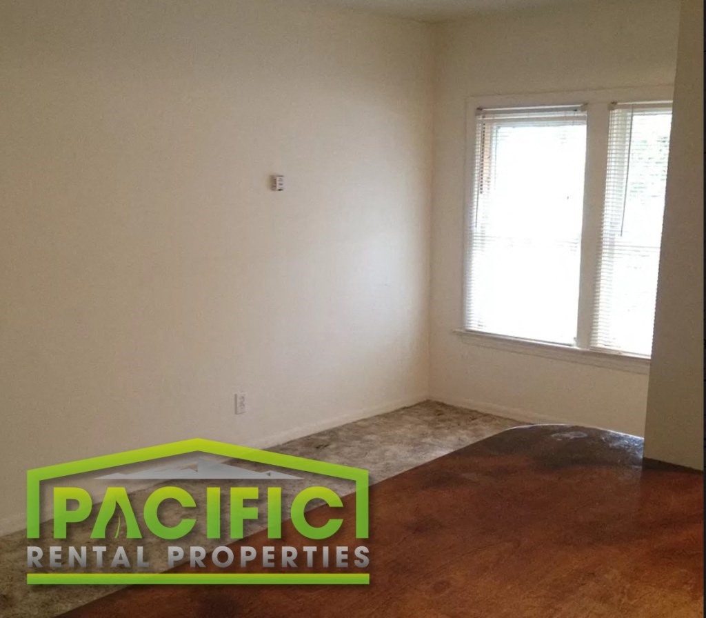 an empty living room with a wooden floor and a window