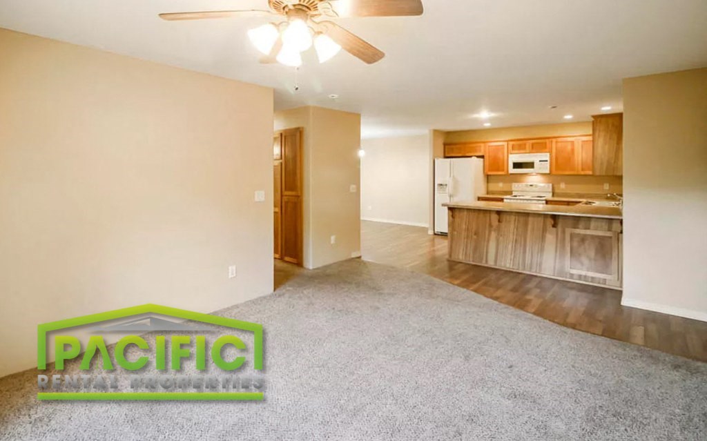 a empty living room and kitchen with a ceiling fan