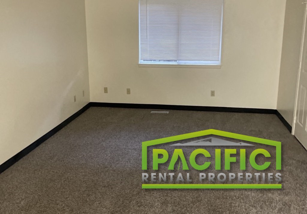 an empty room with a pacific rental properties logo on the floor