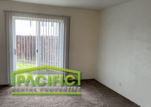 an empty living room with a window and a carpet