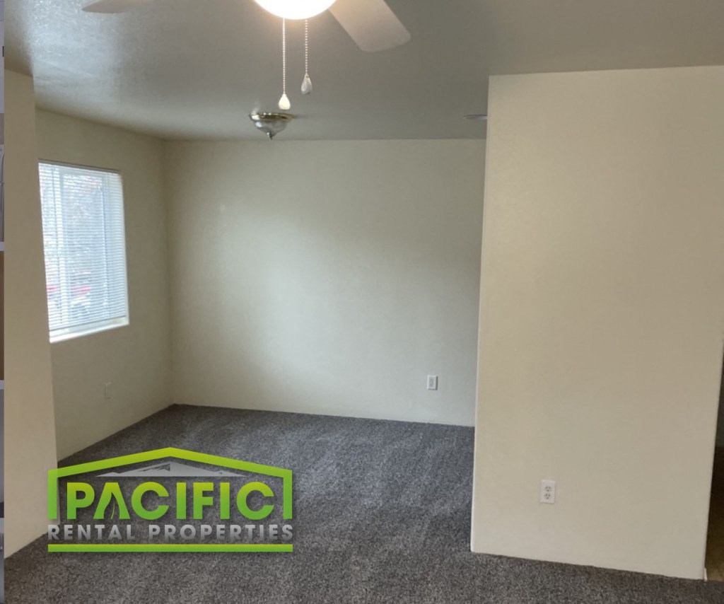 an empty room with a carpeted floor and a ceiling fan