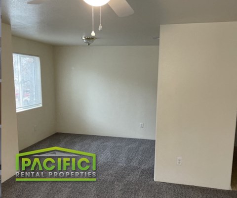an empty room with a carpeted floor and a ceiling fan
