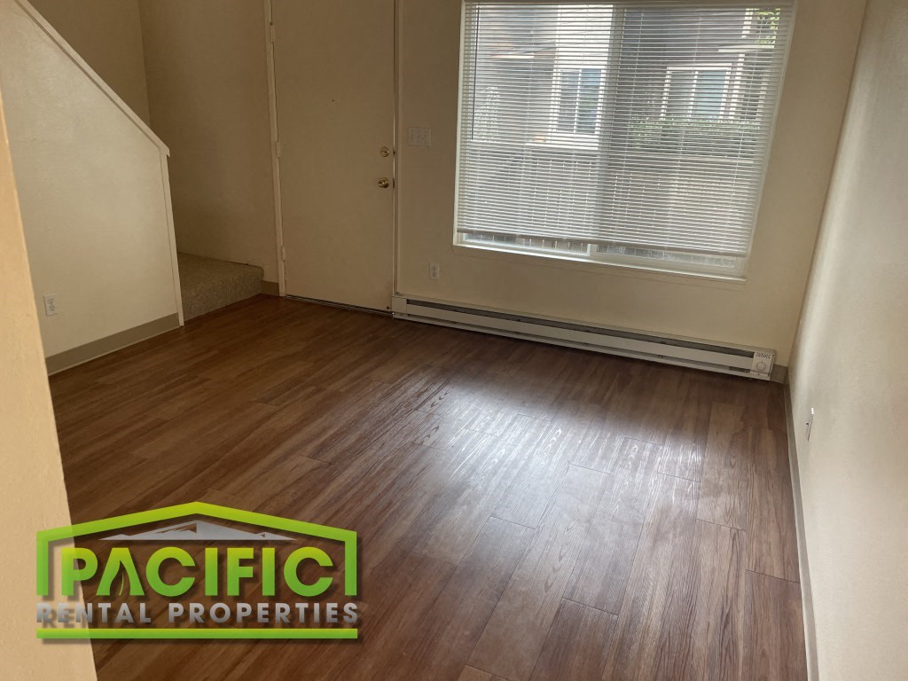 a renovated living room with wood floors and a window