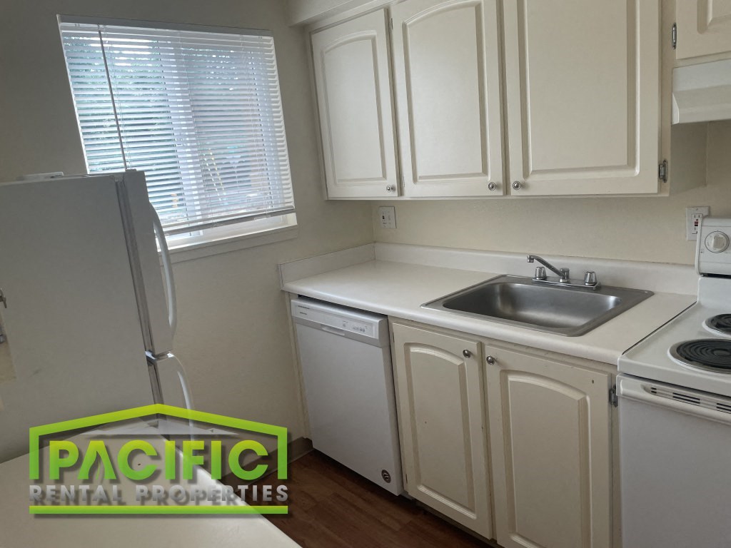 a kitchen with white cabinets and a sink and a refrigerator