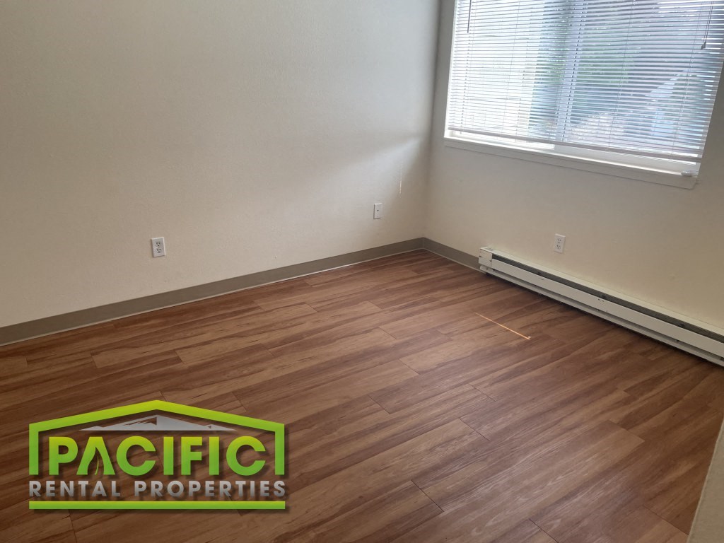 a living room with a wooden floor and a window