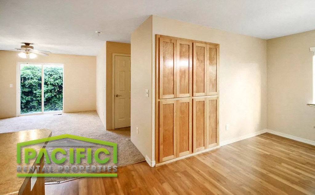 an empty living room with a wooden floor and a closet