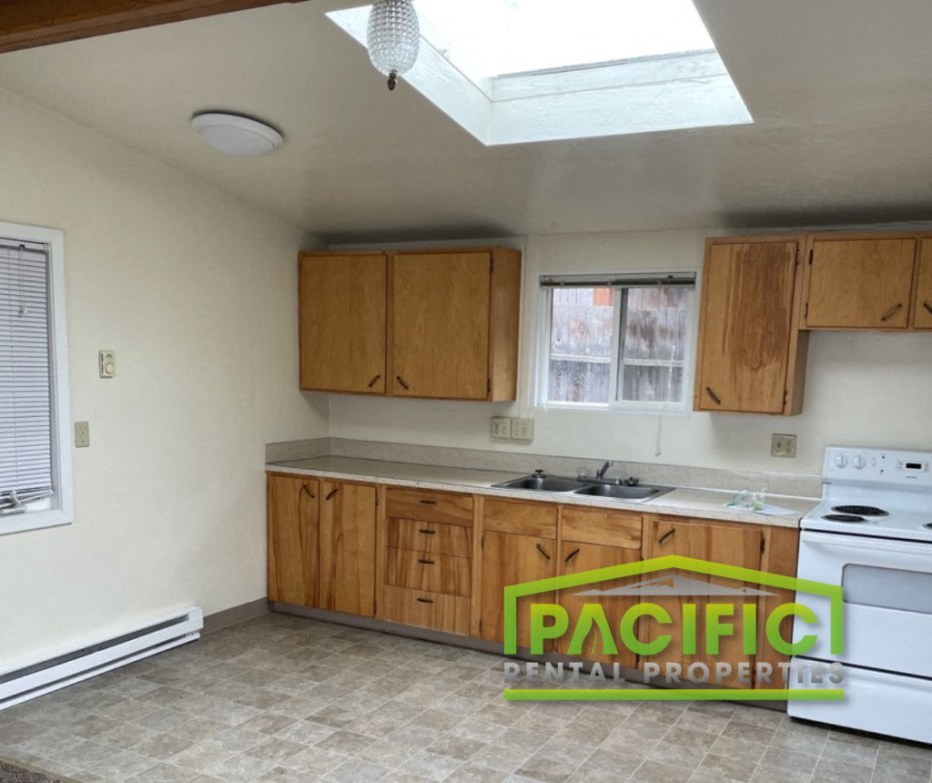 an empty kitchen with white appliances and wooden cabinets