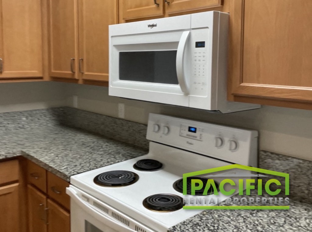 a kitchen with a white stove and a microwave above it