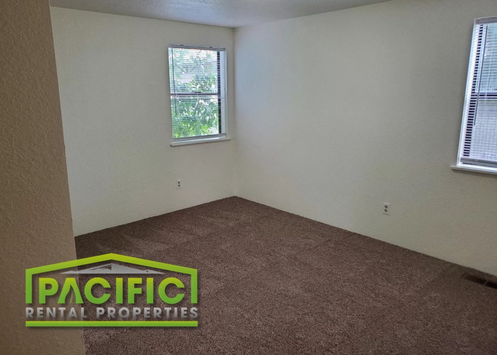 the interior of an empty room with a carpeted floor and two windows