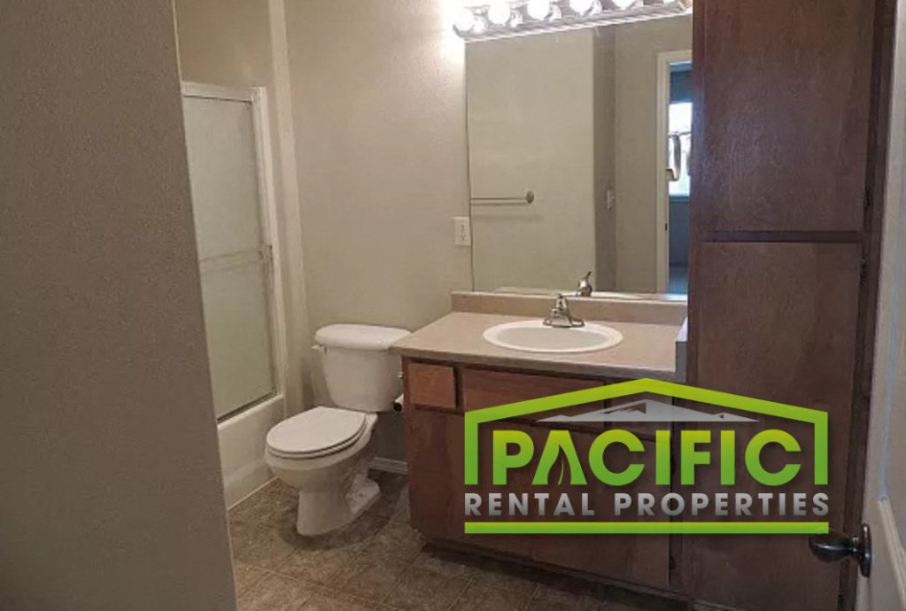 a bathroom with a sink toilet and a pacific rental properties sign