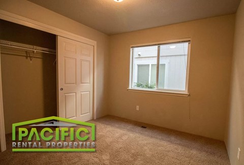 the bedroom of an empty house with a closet and a window