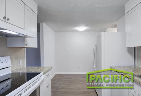 A kitchen with white cabinets and a black countertop.