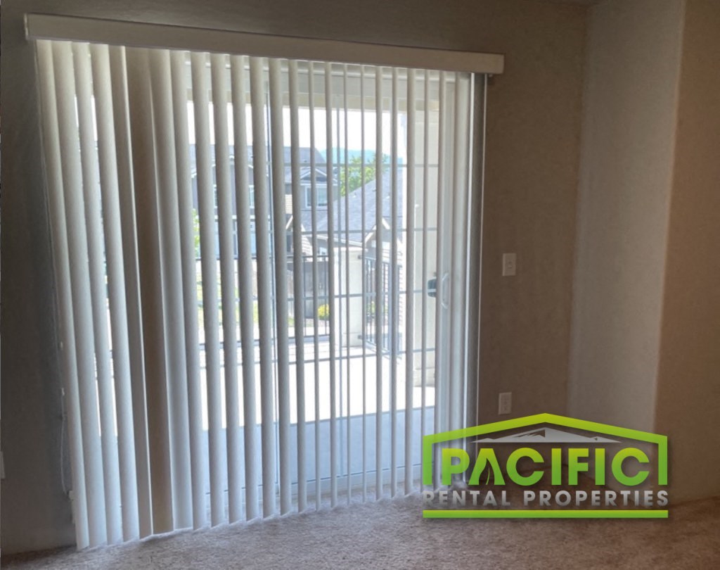 a sliding glass door with vertical blinds in a living room