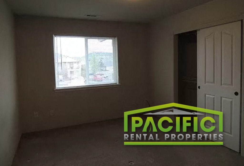 an empty room with a window and a pacific rental properties logo