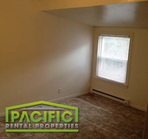 an empty room with a window and a carpeted floor