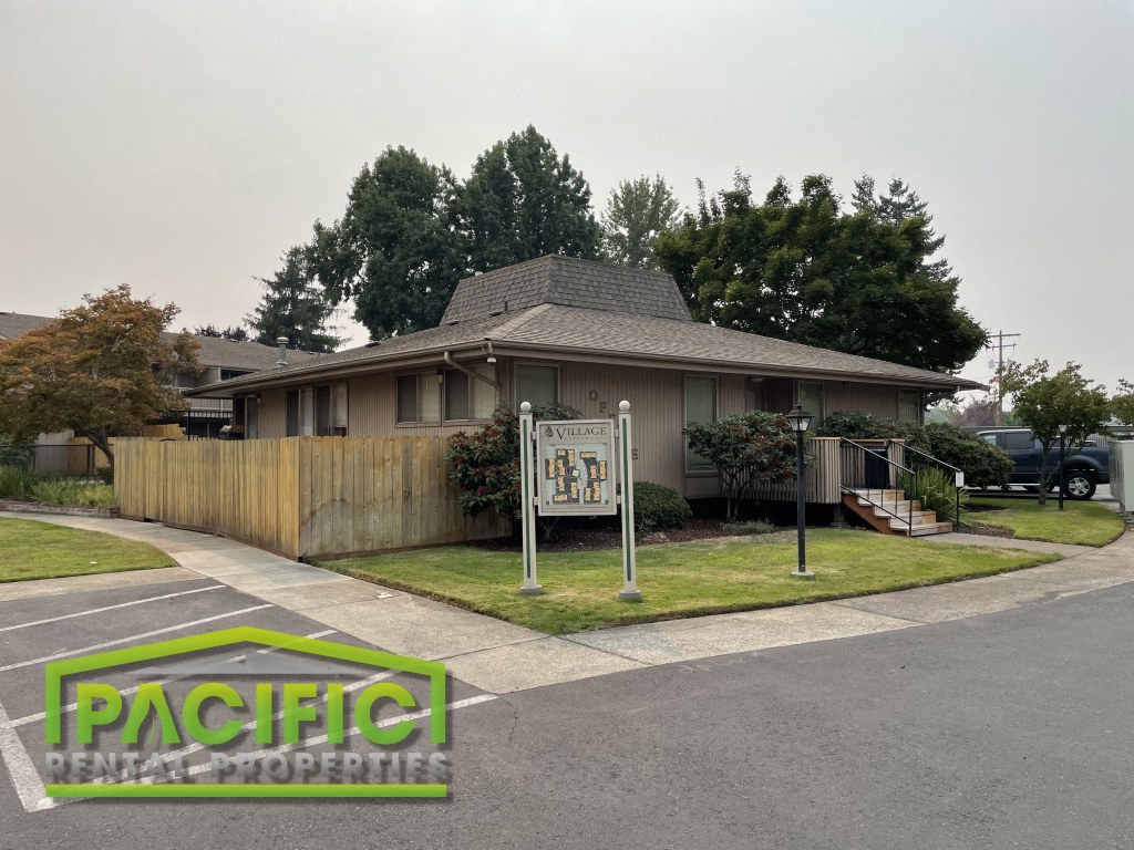a house with a wooden fence and a sign in front of it