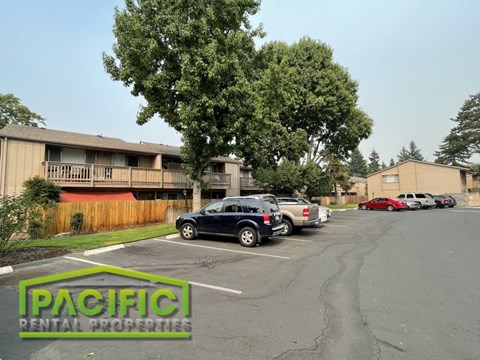 a parking lot with cars in front of an apartment building