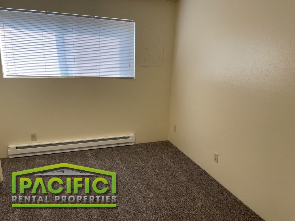 an empty room with a window and a pacific rental properties logo on the floor