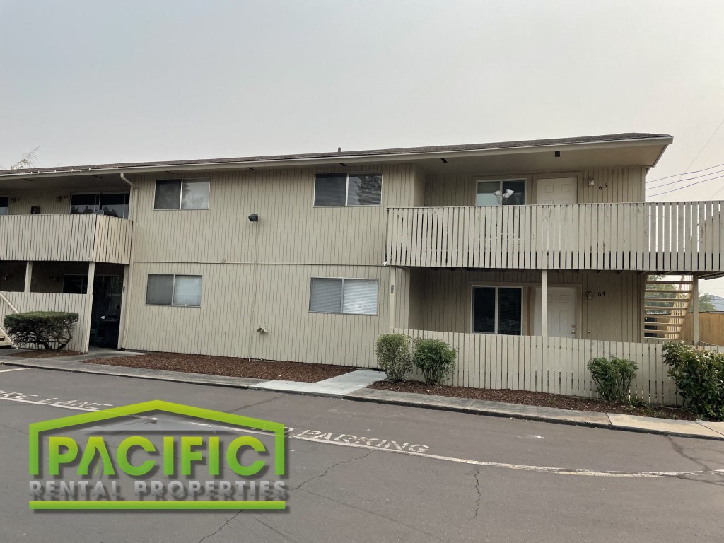 an apartment building with a parking lot and a pacific rental properties logo