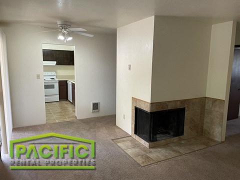 an empty living room with a fireplace and a ceiling fan