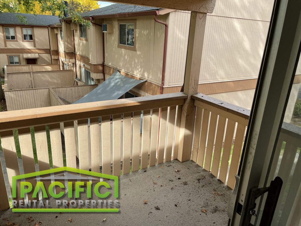 a balcony with a wooden railing and a house in the background