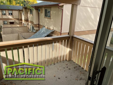 a balcony with a wooden railing and a house in the background