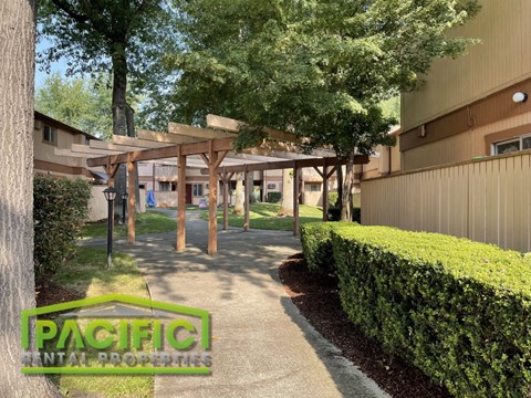a pathway leading to a building with trees and bushes