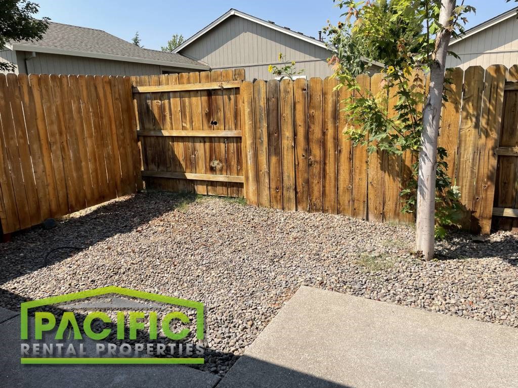 a backyard with a wooden fence and a yard with gravel