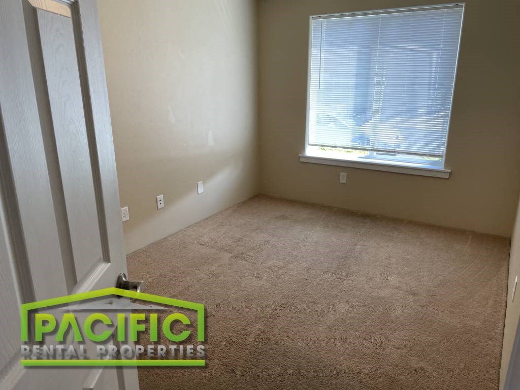 an empty room with a window and a carpeted floor