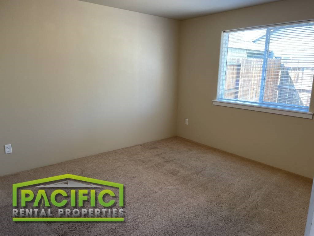 an empty room with a window and a pacific rental properties logo on the carpet