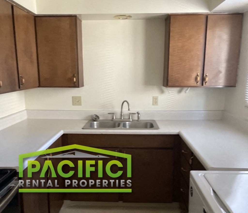an empty kitchen with a pacific rental properties sign on the counter