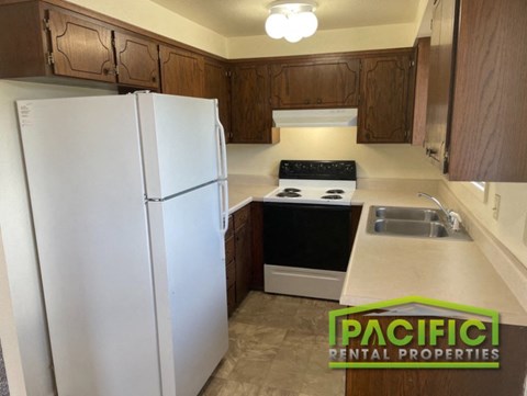 a kitchen with white appliances and wooden cabinets and a refrigerator