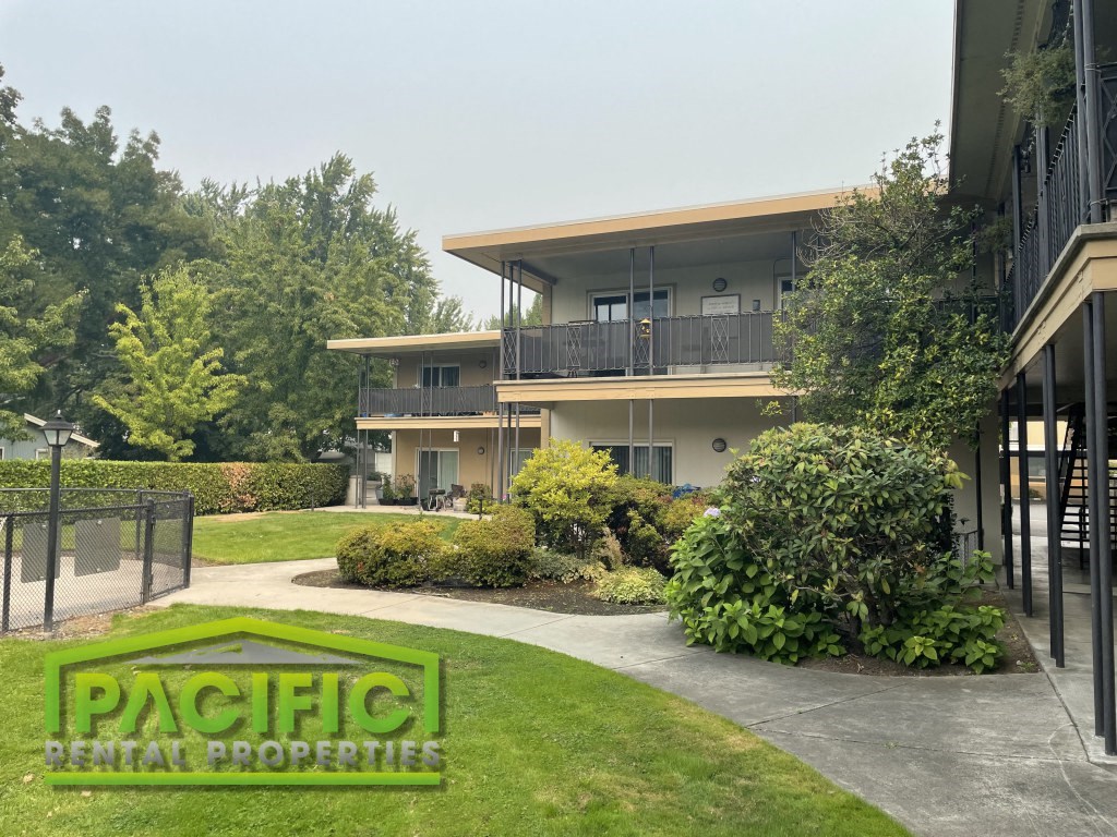 an apartment building with a yard and a sidewalk