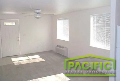 an empty room with a ceiling fan and a door