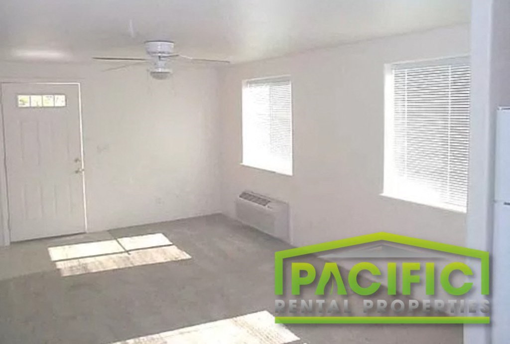 an empty room with a ceiling fan and a door