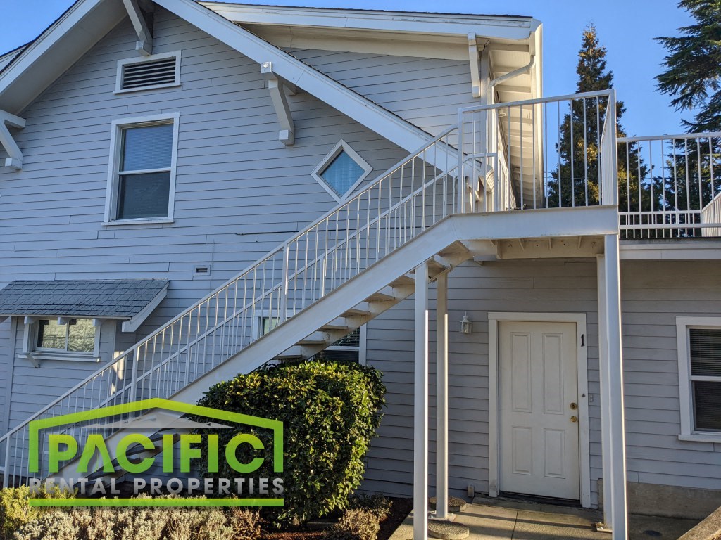 a white house with stairs and a pacific real properties sign
