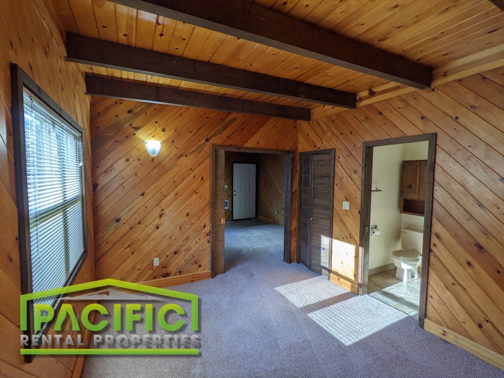 the interior of a wooden cabin with a carpeted floor and a bathroom