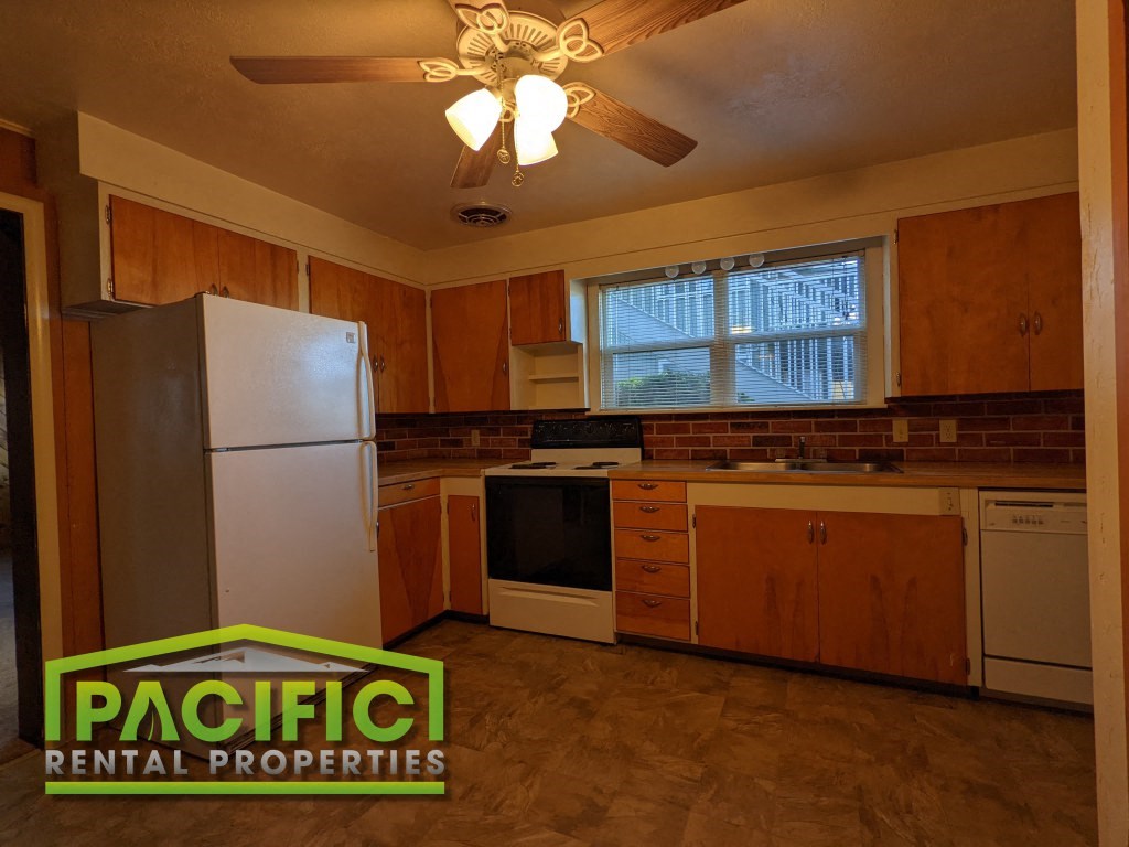 a kitchen with wooden cabinets and a refrigerator and a ceiling fan