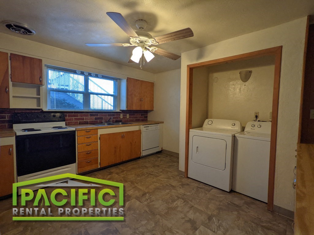 a kitchen with a washer and dryer and a ceiling fan