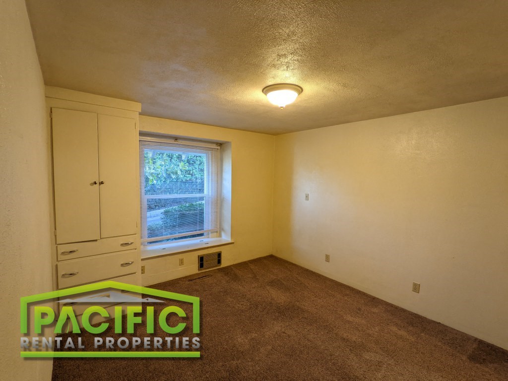 the bedroom of a house with a carpeted floor and a window
