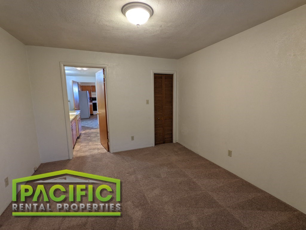 an empty living room with carpet and a door to a bathroom