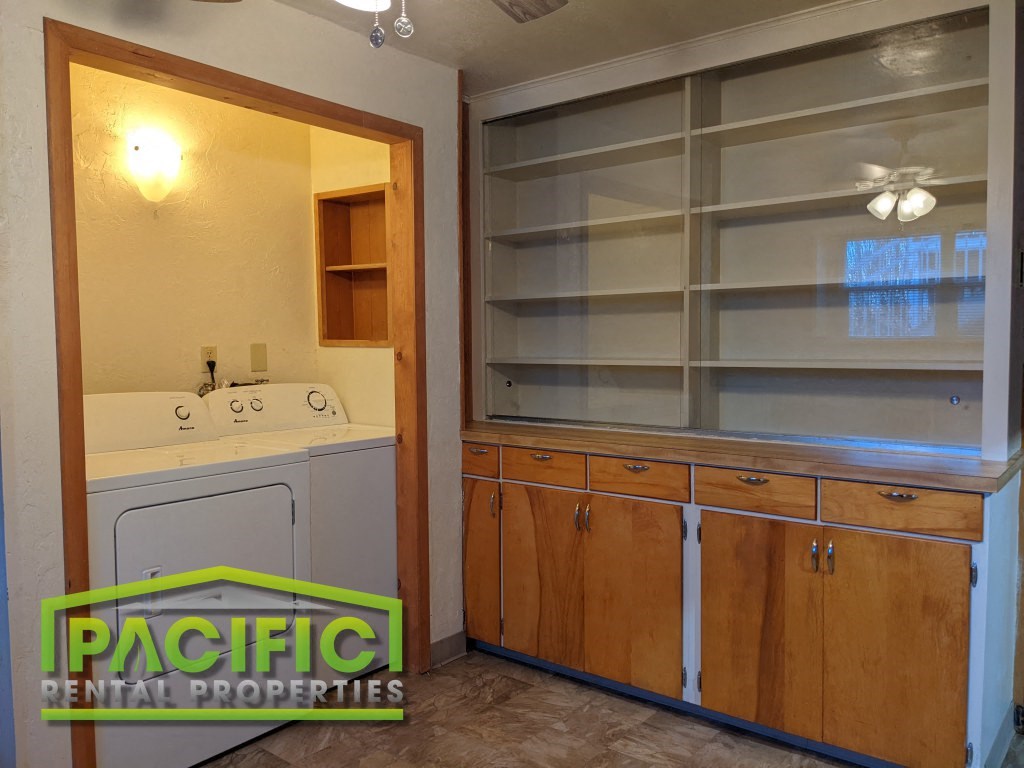 a laundry room with a washer and dryer and a cabinet with shelves