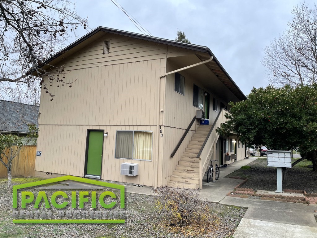 the front of a house with stairs and a green door