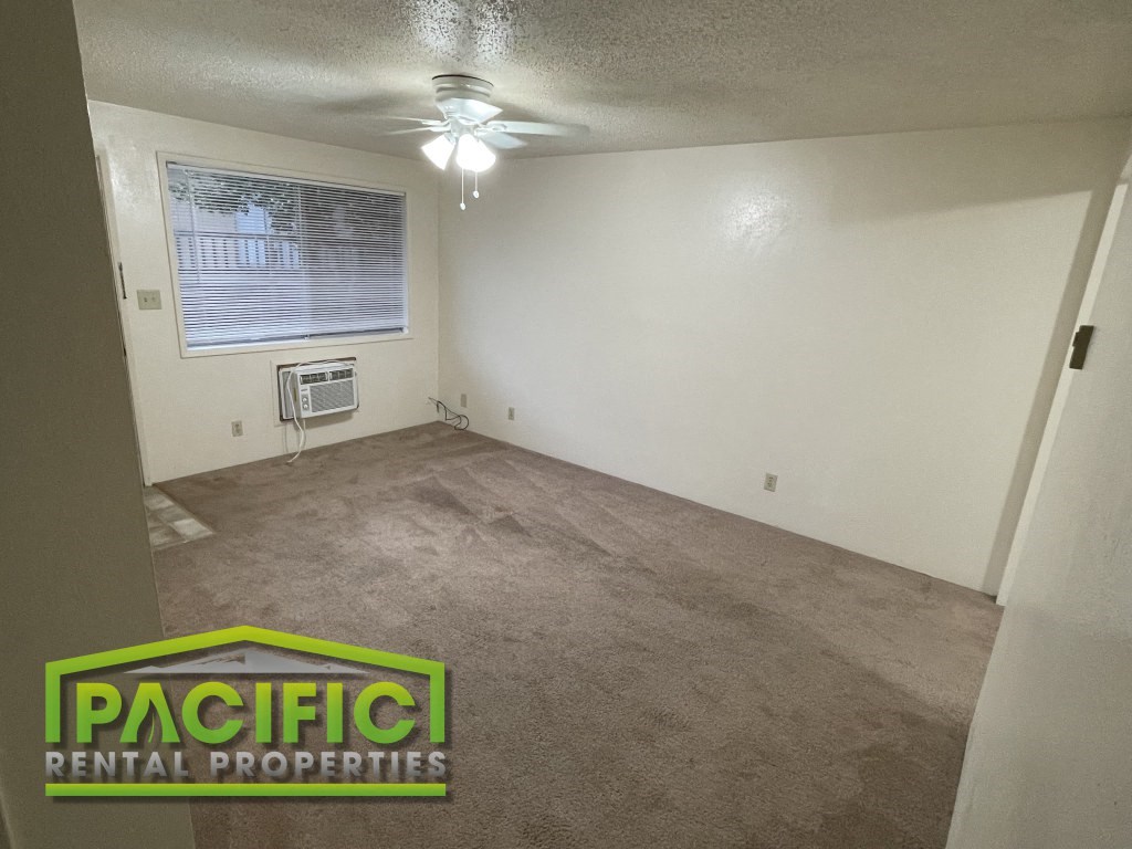 the living room of an empty house with a ceiling fan