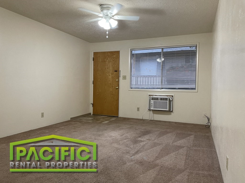 an empty living room with a ceiling fan and a window
