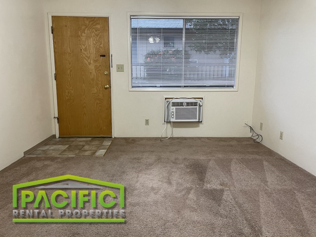 an empty room with a window and an air conditioner on the floor